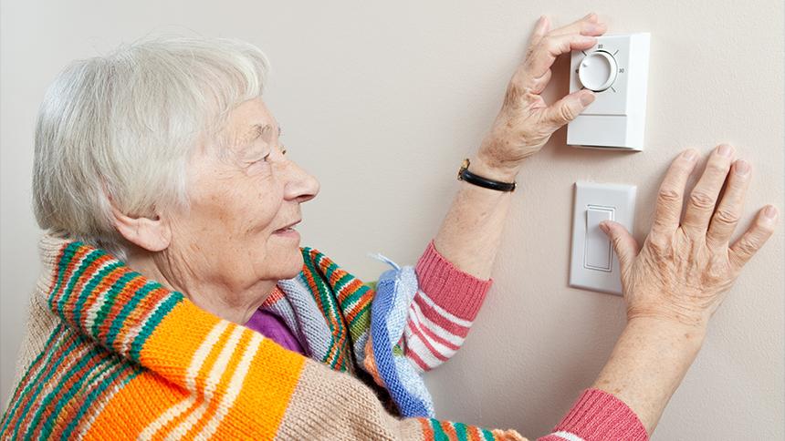 A person adjusting a thermostat