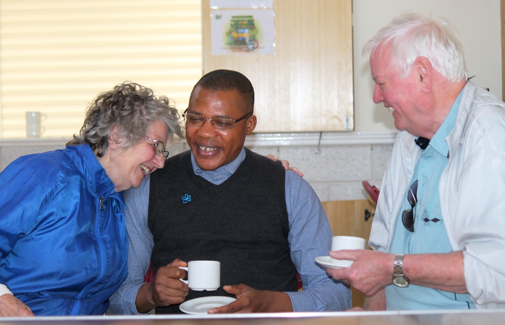 Three people holding tea and laughing
