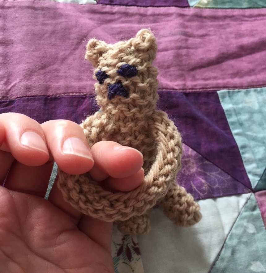 A knitted Snuggle Bear being held on fingers