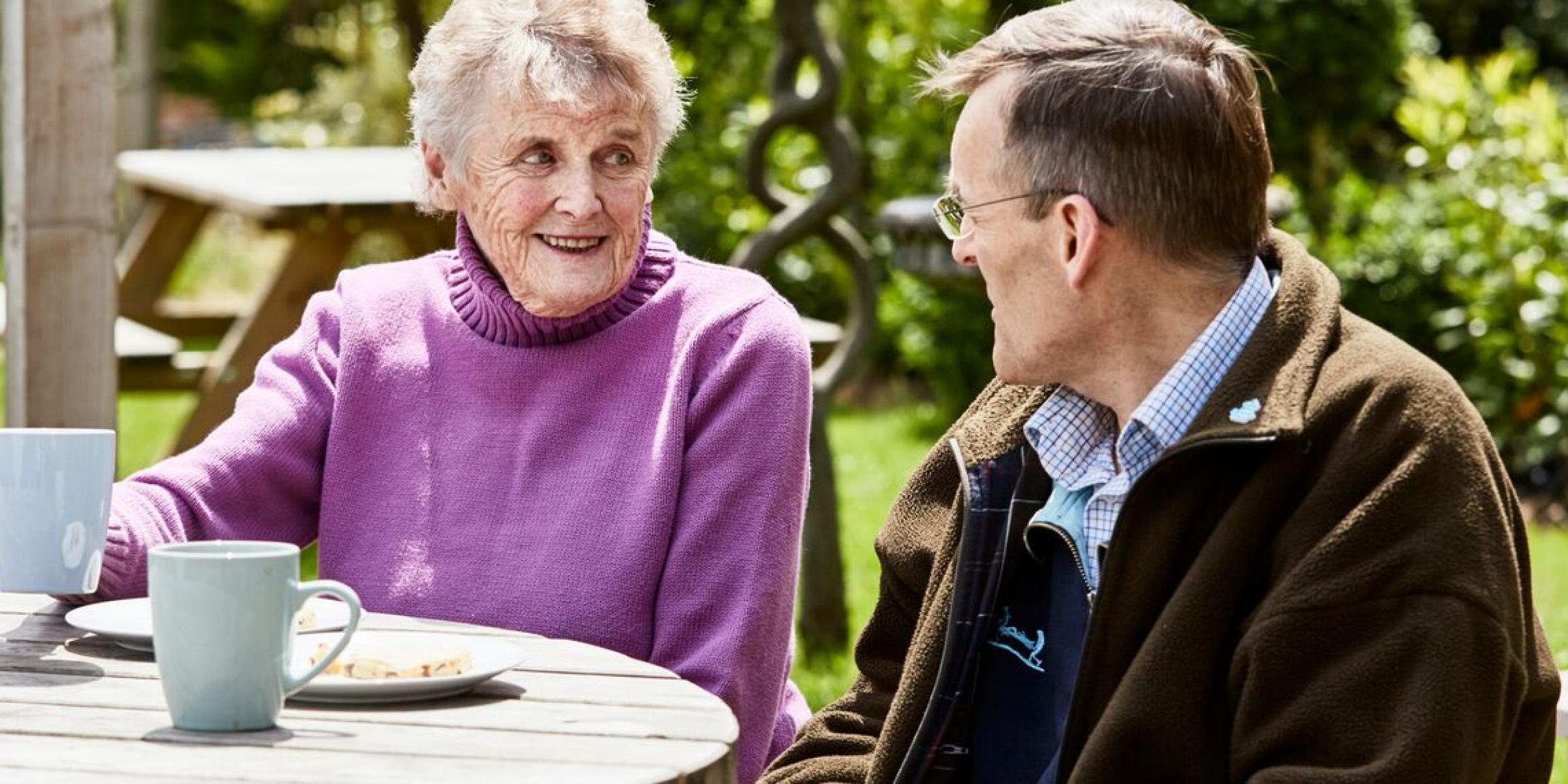 Mark and his mum chatting in the garden with tea