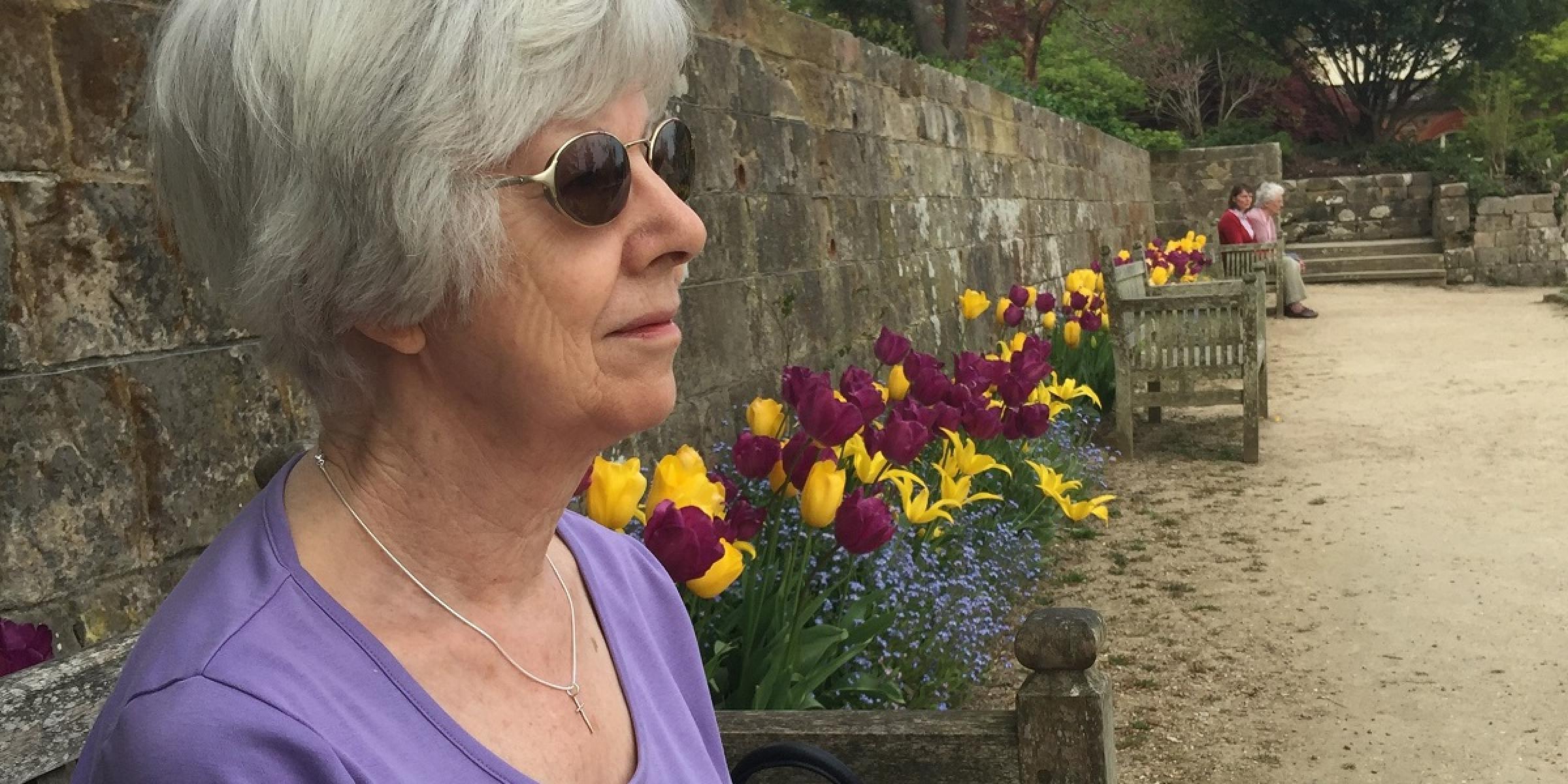 Jonathan's Mum sitting outside next to flowers