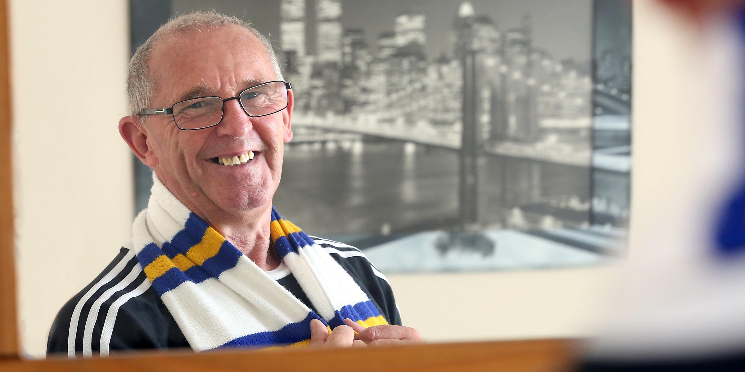 Andy Paul looking in the mirror, wearing a Leeds United scarf.