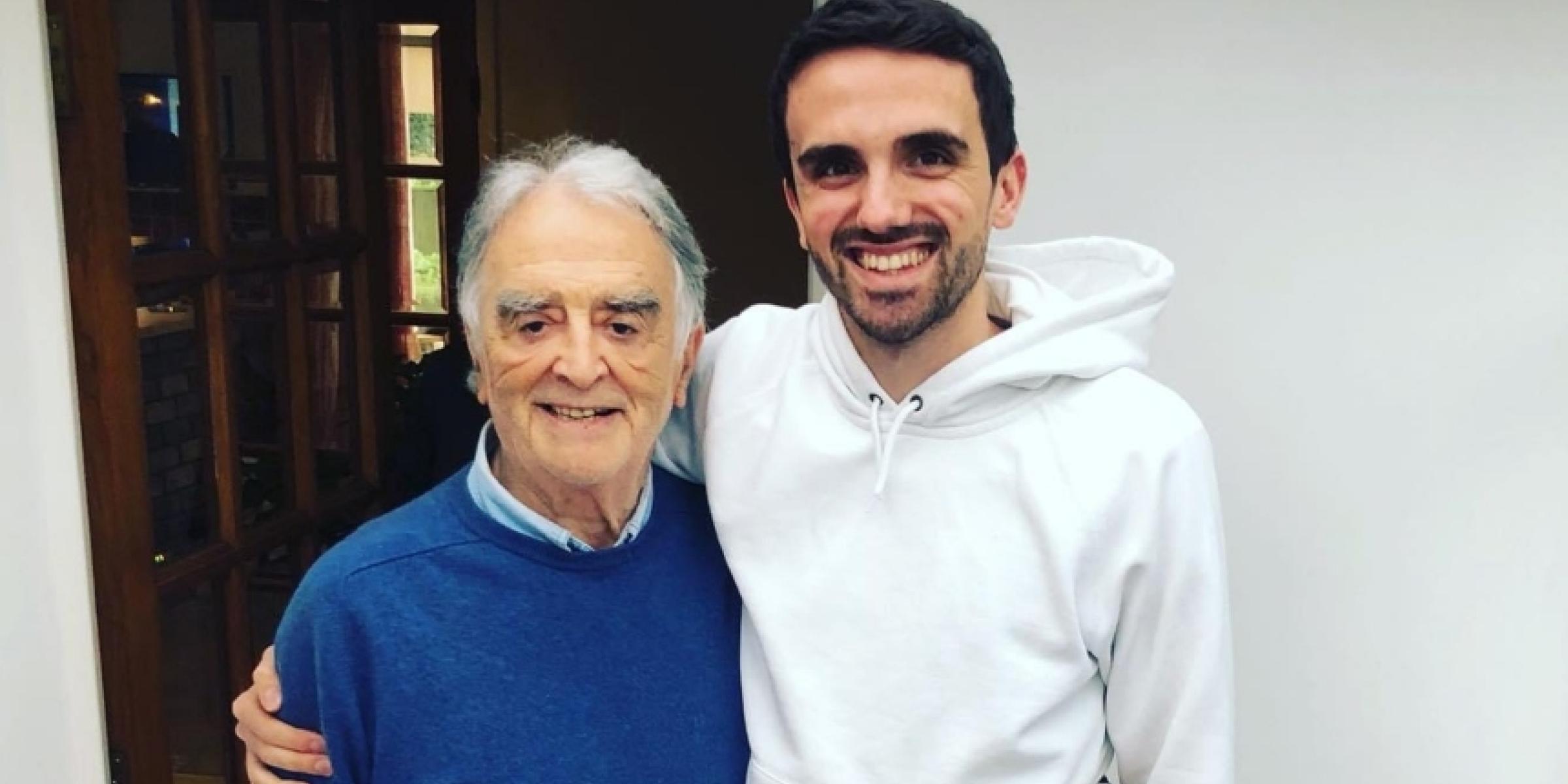 Charlie with his arm round his grandad. Both of them are smiling.