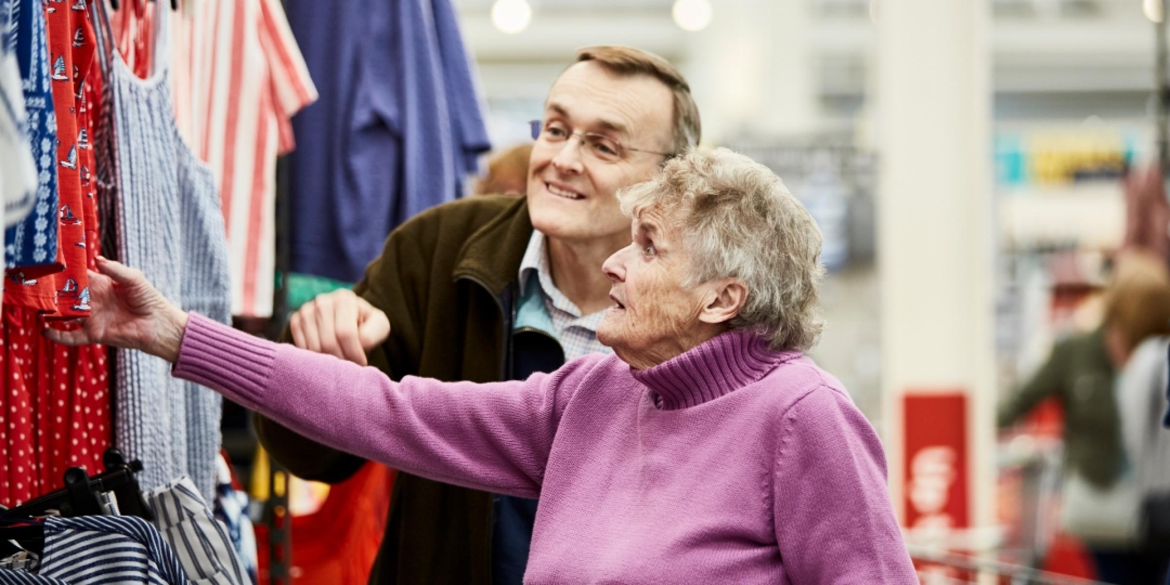 A person with dementia looking at clothes in a shop with a family member