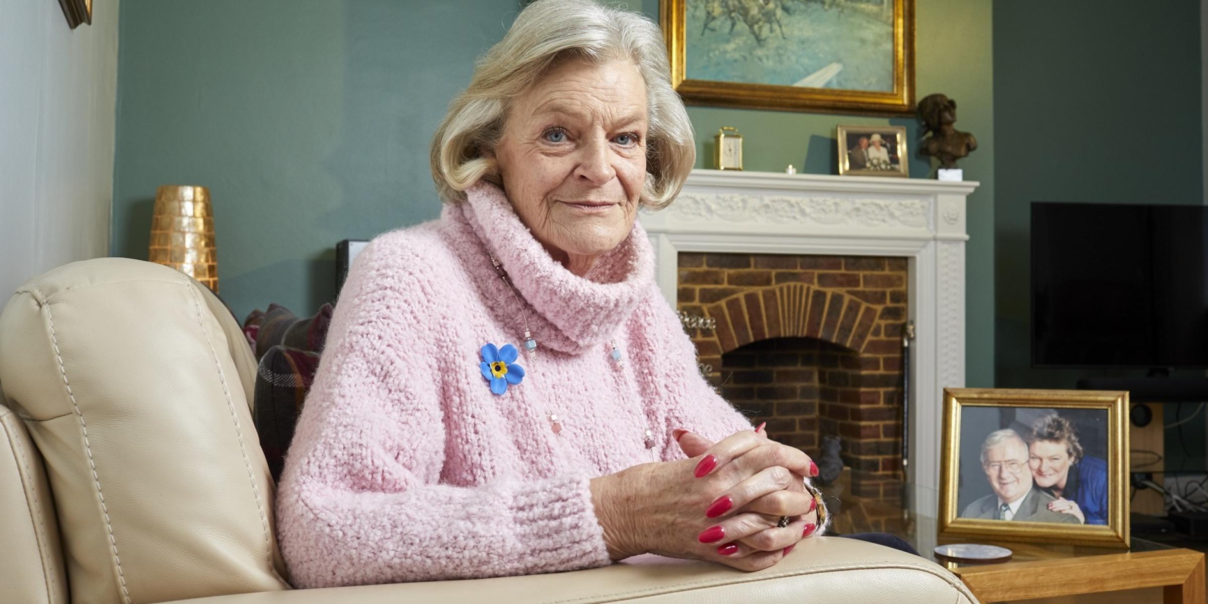 Liz sitting in her living room in front of a photo of her and Eric