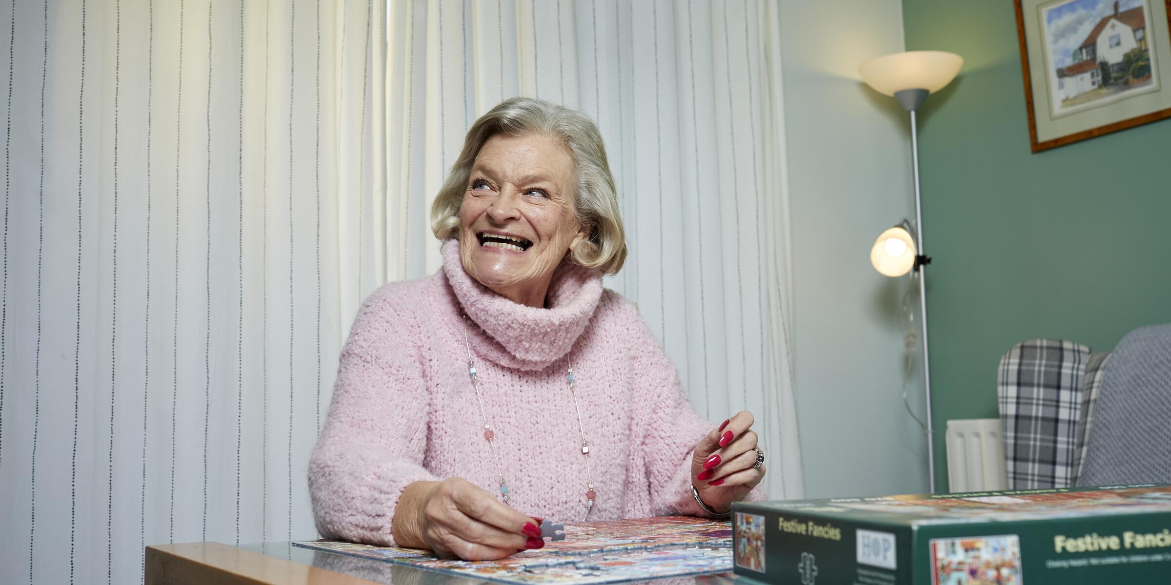 a woman sits at the table with a jigsaw puzzle