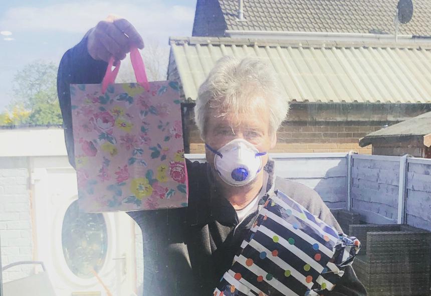 Alex's dad, Dave, holding a gift bag and wearing a facemask