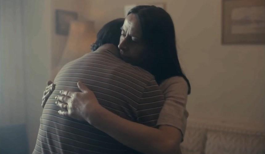 A woman is embracing a man, her husband, in their house