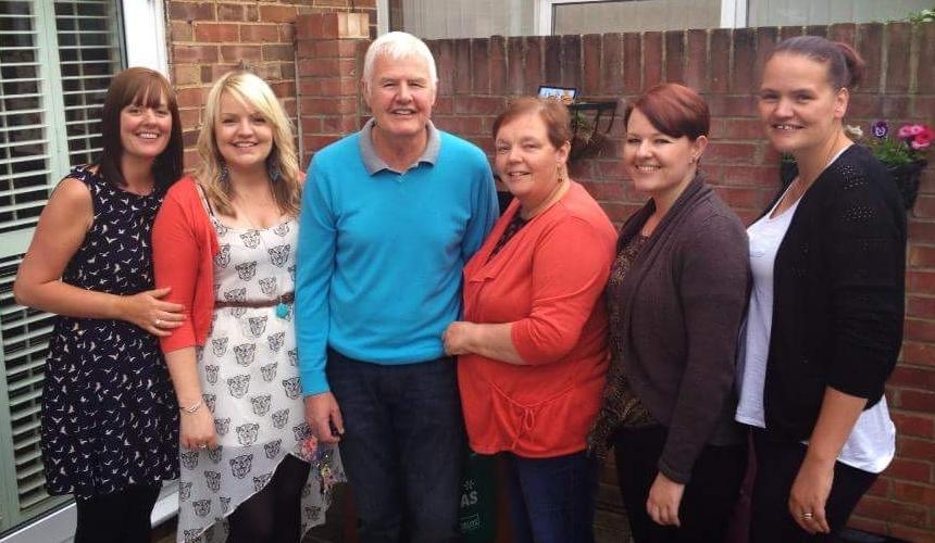 Jen with her parents and three sisters, standing together in the garden, smiling