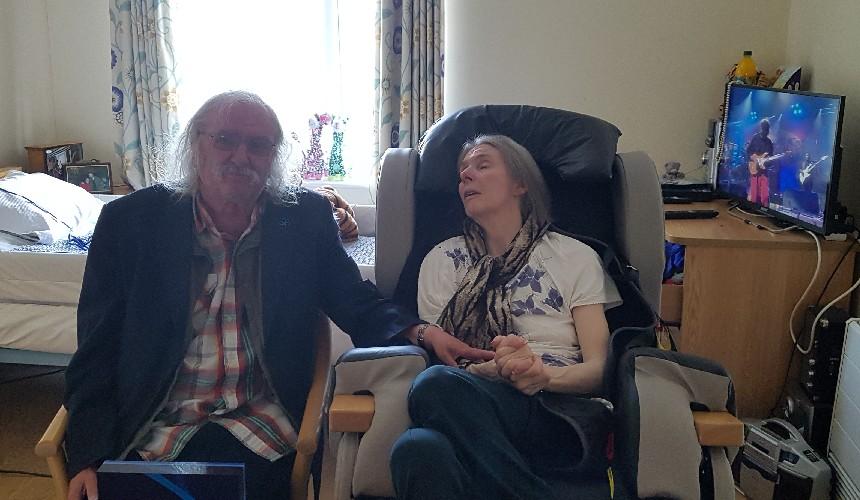 Graeme visiting Ann while music plays on the TV