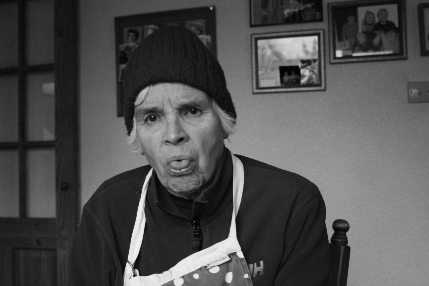 Kyra's grandma, Winifred, wearing a hat and apron and sticking her tongue out towards the camera