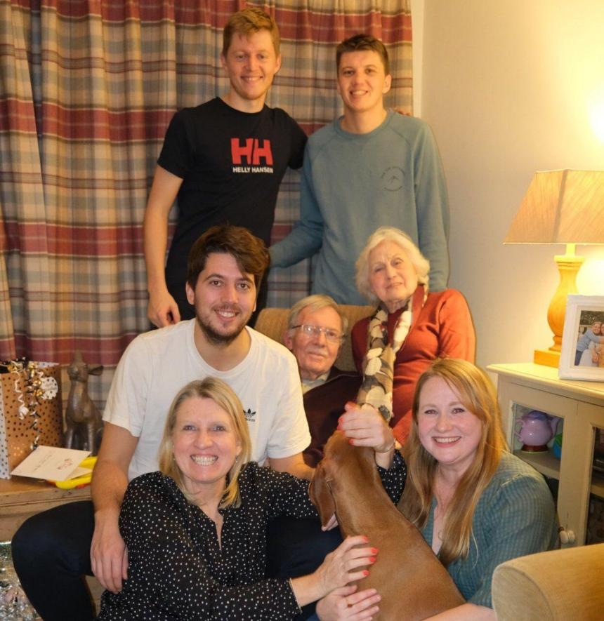 Stan with his wife, two daughters, three of his grandsons and the family dog posing for a family picture in the living room