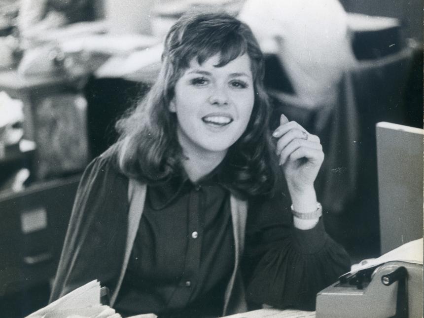 Black and white photo of Cara's mum Anita working in an office in front of a typewriter, styled like it might be during the 1960s
