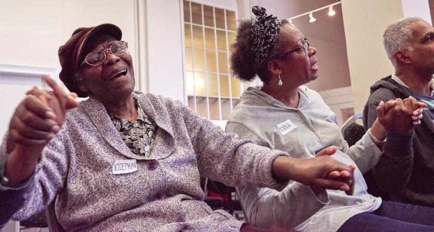 Three people singing while holding hands