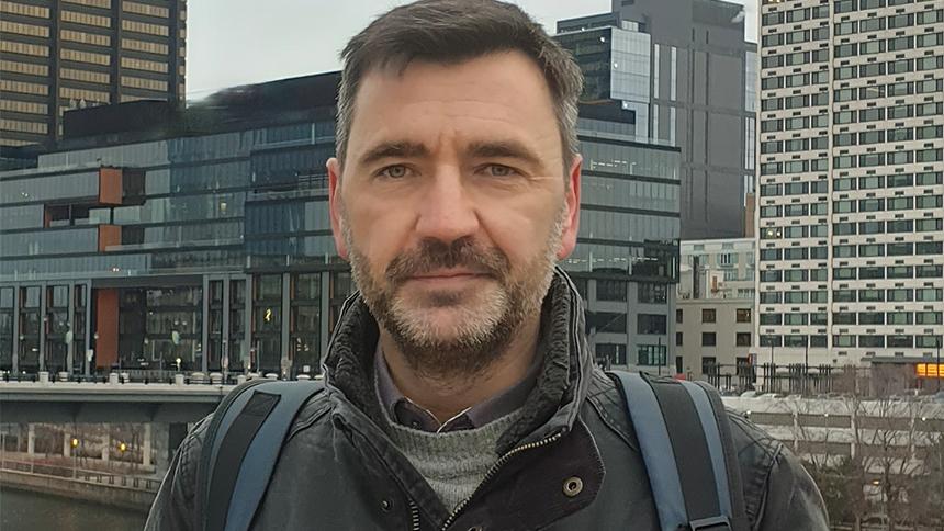 Professor Geoff Parker standing in front of some modern glass buildings