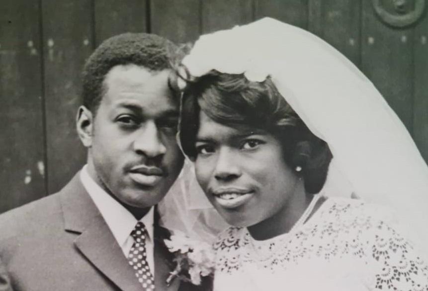 Raymond and Cynthia stand next to each other in wedding clothes
