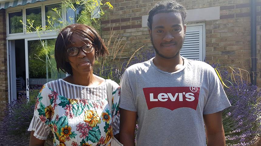Jonathan Knight and mum Christine stand outside, smiling, on a sunny day. Christine is in sunglasses and a floral top and Jonathan is in a t-shirt.