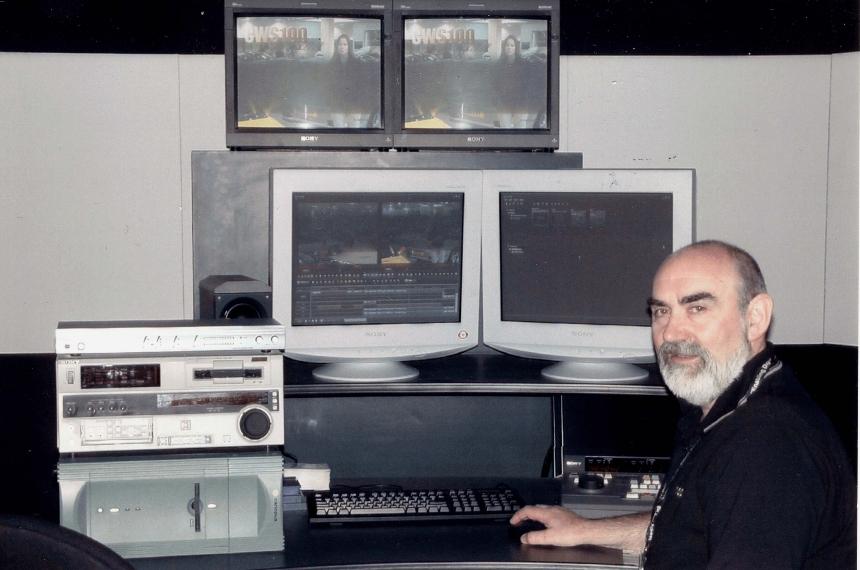 Ian sitting at a desk with computer monitors