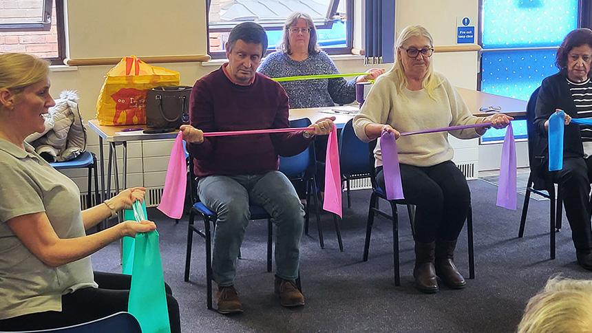 Sit to keep fit participants use resistance bands to build arm strength