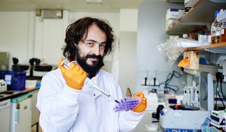 A scientist or researcher smiling as they do tests in a lab