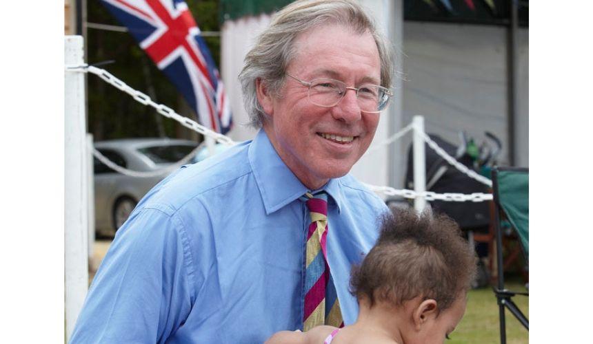 Tony Gall smiling, holding a young girl's arm