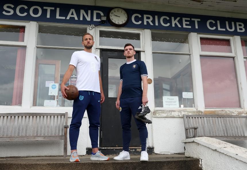 England captain, Kane, and Scotland captain, Robertson, stand with an old style football and football boots