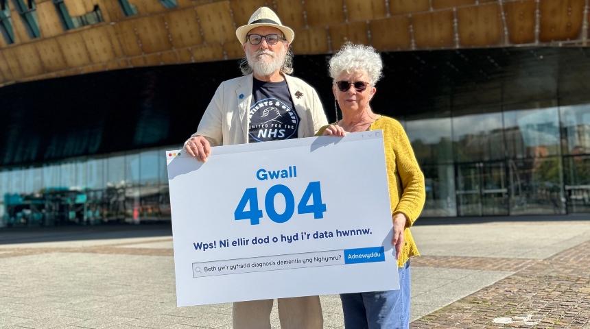 2 people stood holding a sign that says 'error:404'