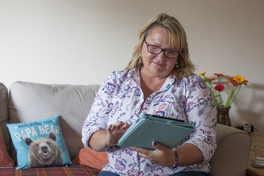 woman sat on the sofa looking at her tablet
