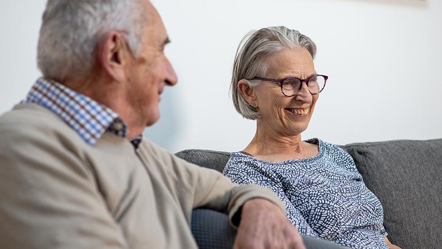 Anne and Tony Hoad sit on their sofa in their home together.