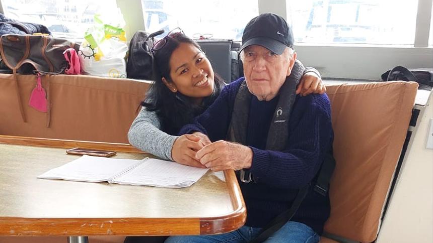 Daisy and Roy Timms sit together in an embrace on a boat. Roy is wearing a buoyancy aid and a baseball cap.