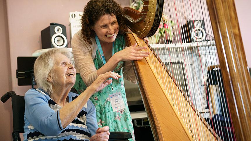 A care home resident shows interest in the harp being played by Eleri Darkins