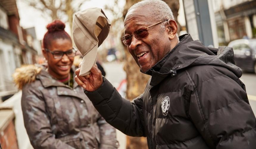 Person smiling and taking his hat off