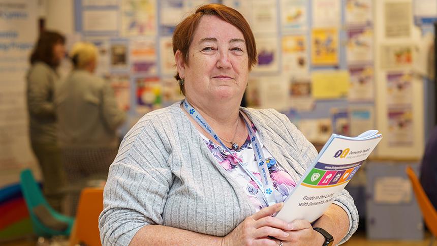 Dawn Davies in Swansea's Dementia Hwb, holding information materials and looking into camera