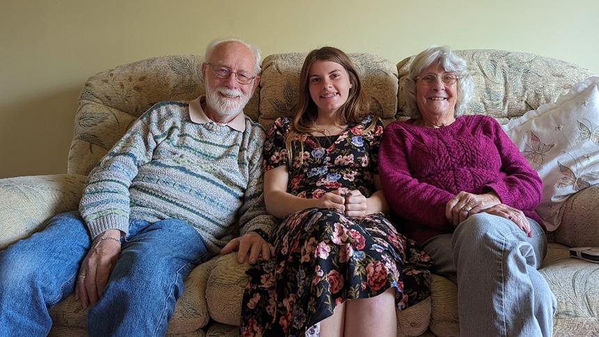 Brenda and her husband Alan sat on a beige sofa with their granddaughter