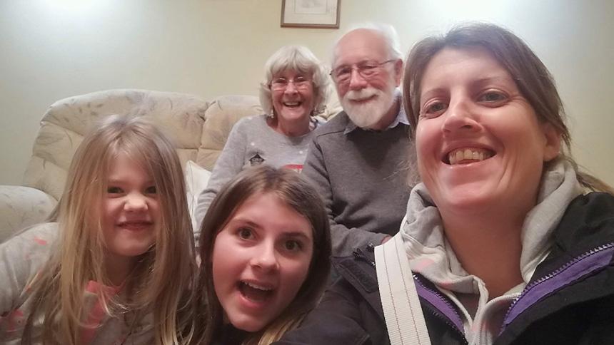 Brenda and her husband sat on a beige sofa with two granddaughters and Brenda's daughter sat in front of them