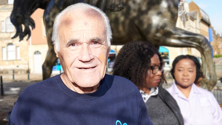 Bryan Talbot outside wearing a navy blue Alzheimer's Society t-shirt stood in front of a horse statue
