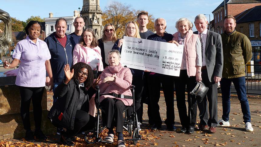 Bryan and Sheila Talbot present a group of people with a cheque on a sunny day