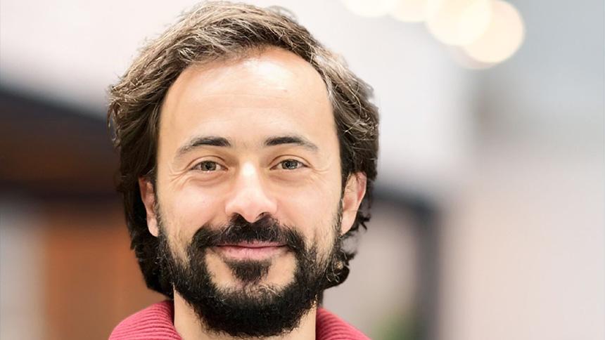 Hugo Fernandes smiling at the camera and wearing a red top.