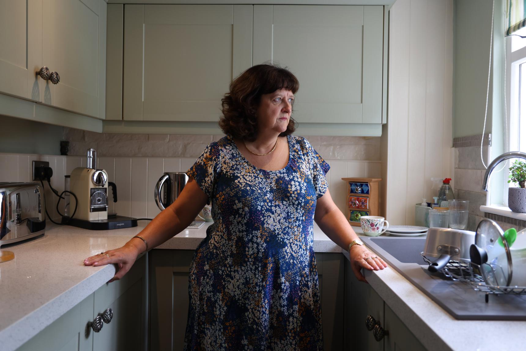 Jane stands in her kitchen and looks out the window