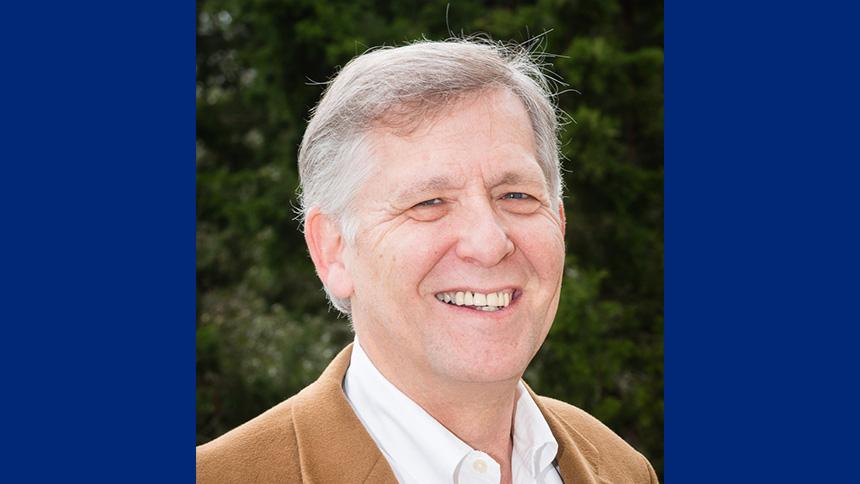 Stephen of Theora 360 outdoors smiling and wearing a camel-coloured jacket and white shirt
