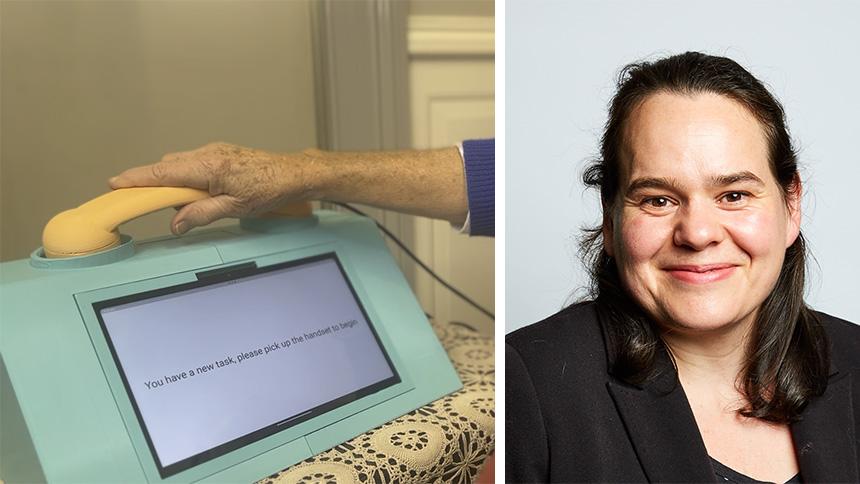 MemoryAid technology featuring large screen with in-built yellow telephone handset. Celia from MemoryAid team smiling, she has shoulder-length brown hair and is wearing a black jacket.