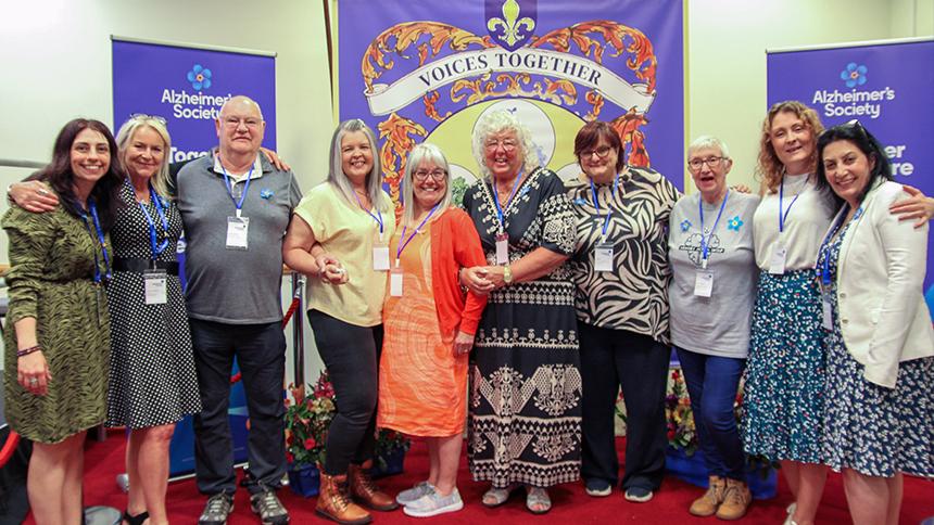 Ten people stood in a row, in front of Alzheimer's Society banners