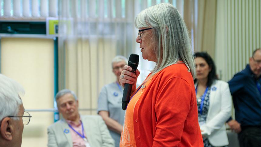 Carer speaking on a microphone to a room of people