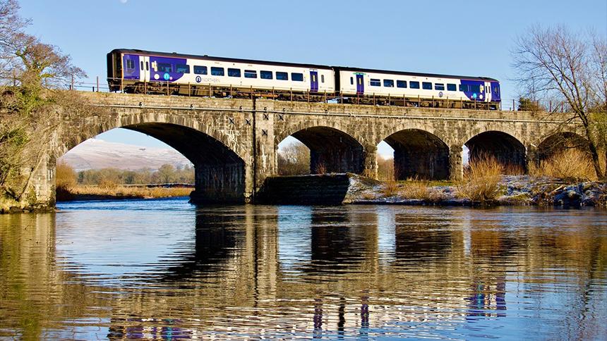 Two carriage train crossing a bridge over a river