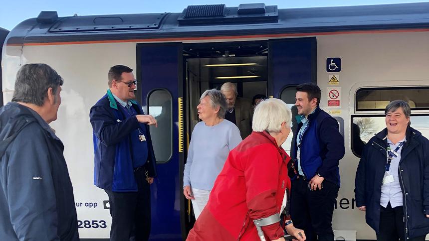 Uniformed staff from Northern Rail and members of the public on a train platform, next to an open train door