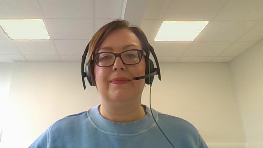 Denise Maguire from the Dementia Support Line wearing a headset and blue jumper