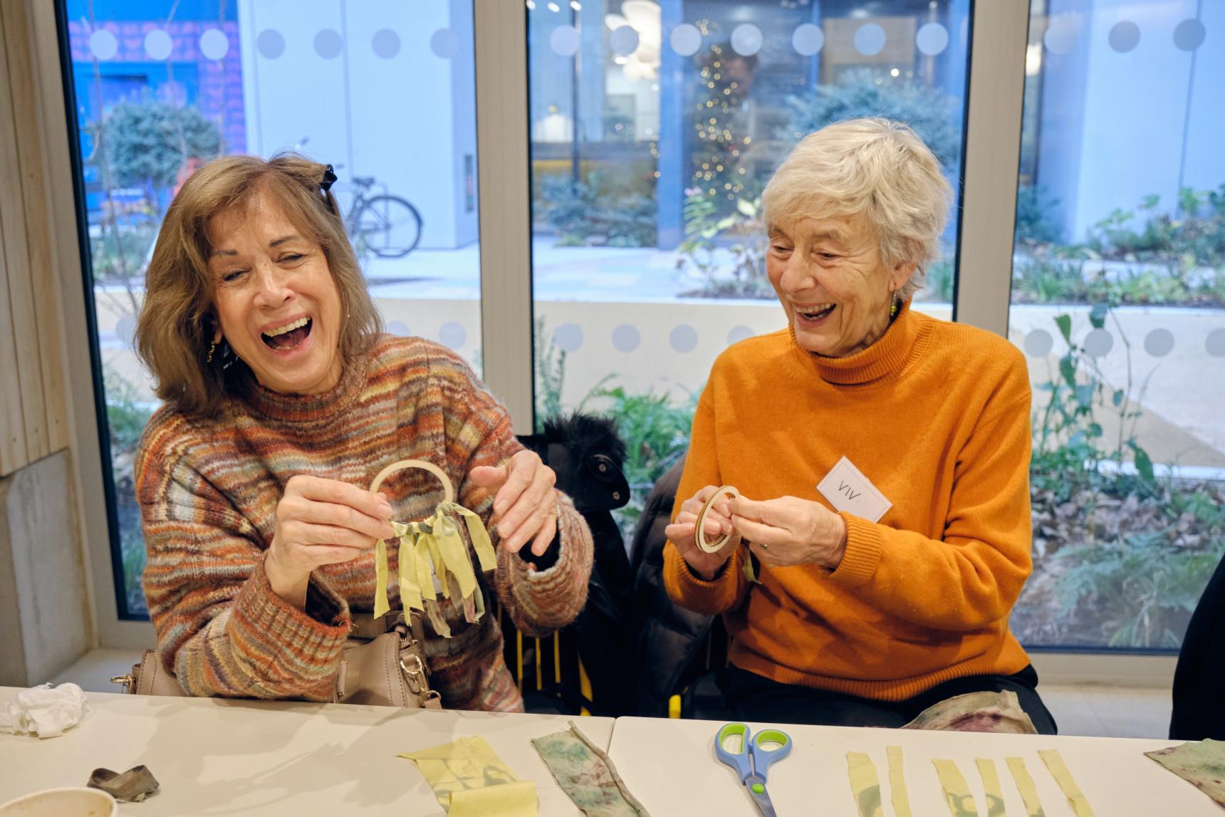 Two women doing crafts at a table, laughing