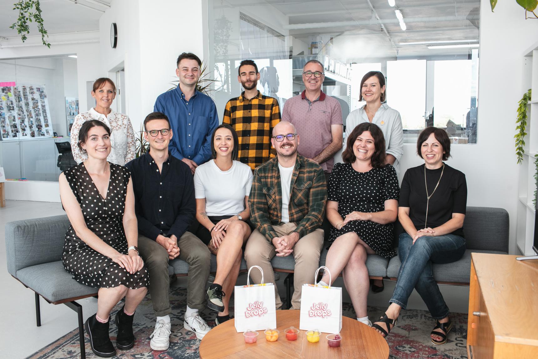A team of people sit together for a group photo in their office 
