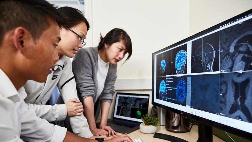 Three researchers looking at brain scans