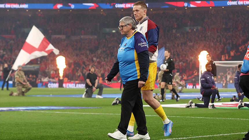 Susan and Jordan Pickford walking together to the left on the football pitch